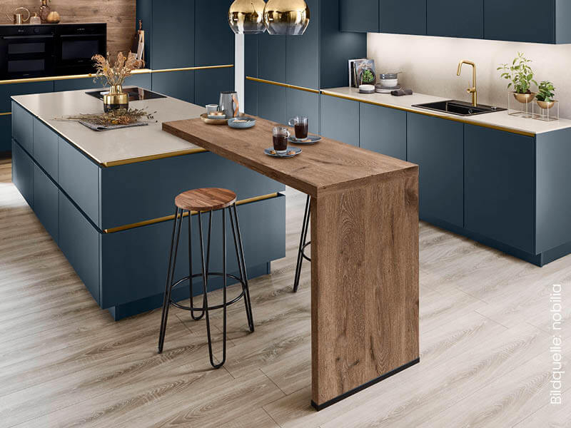 Moderne Küche mit blauen Fronten, goldenen Griffleisten und Holztheke