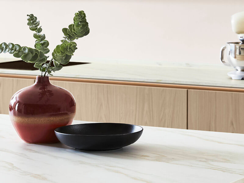 Marmor-Küchenarbeitsplatte mit terrakottafarbener Vase mit Eukalyptus und schwarzer Schale