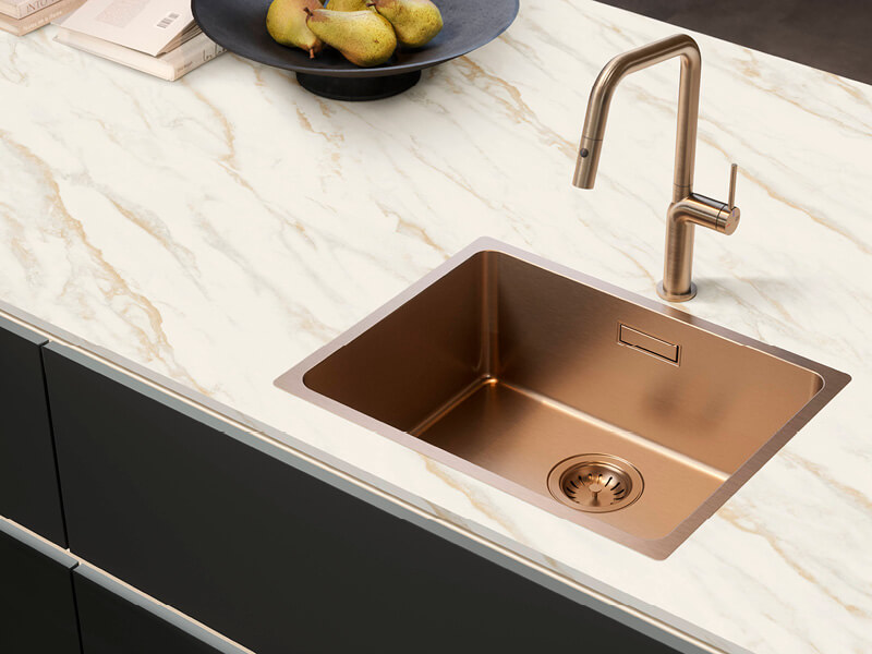 Blick auf Arbeitsplatte in Marmoroptik mit bronzefarbener Spüle und Armatur