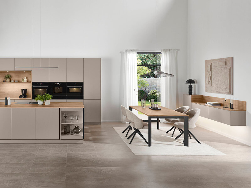 Küche mit sandgrauen Fronten von nobilia mit angrenzendem Essbereich mit Essgruppe und Wandkommode