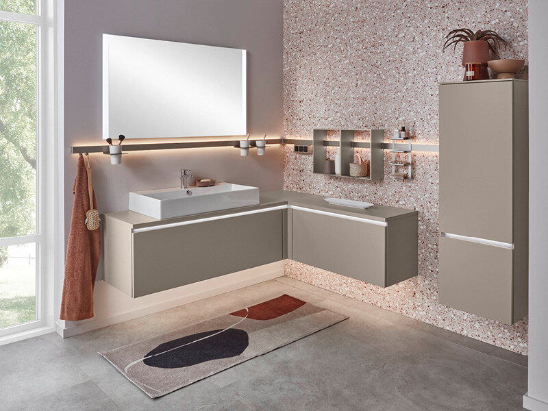 Badezimmer mit beleuchteten Schränken mit sandgrauen Fronten