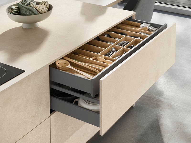 Kücheninsel mit Blick auf geöffnete Schublade mit hellen, fein strukturierten Fronten