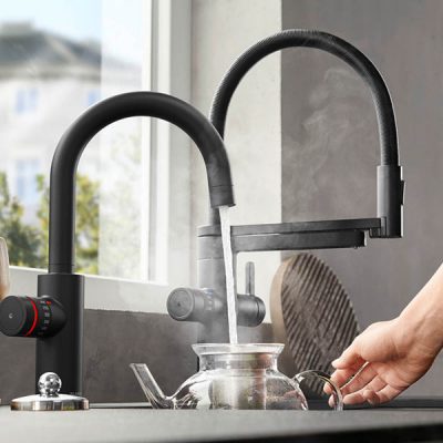 kochend heißes Wasser wird aus Wasserhahn in Teekanne gefüllt