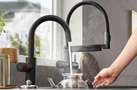 kochend heißes Wasser wird aus Wasserhahn in Teekanne gefüllt