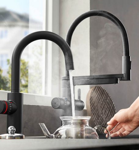 kochend heißes Wasser wird aus Wasserhahn in Teekanne gefüllt