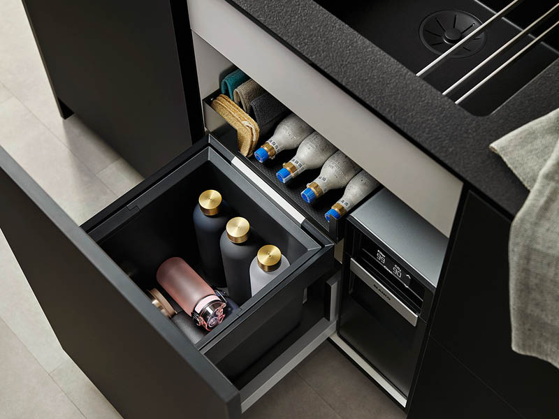 geöffneter Spülenunterschrank zeigt Wassersystem und Sodaflaschen