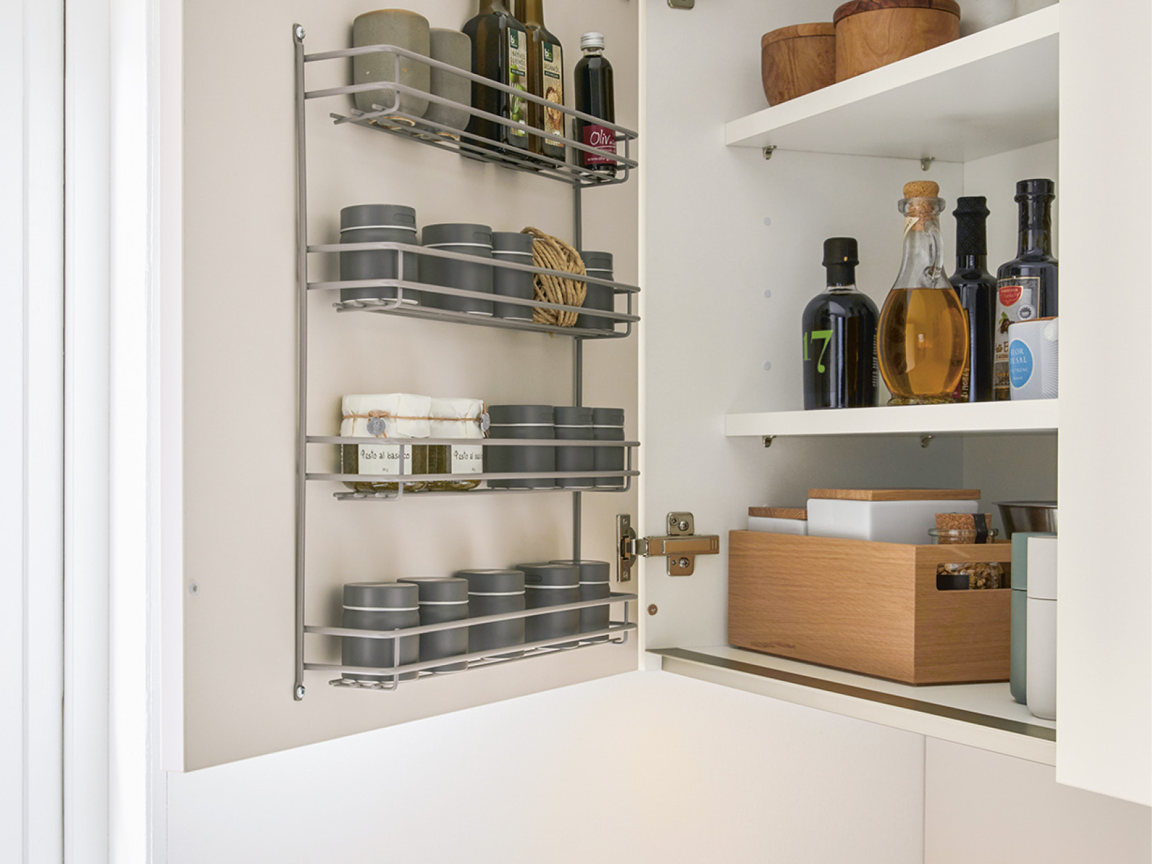 Cleveres Ordnungssystem in kleinen Küchen: Hängendes Gewürzregal an der Innenseite der Schranktür und strukturierte Aufbewahrung für Öle, Essig und Kochzutaten im Oberschrank.