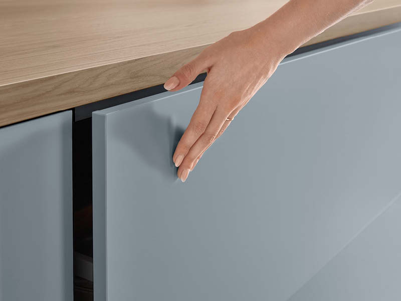 Matte Küchenfront, auf der eine Hand liegt.