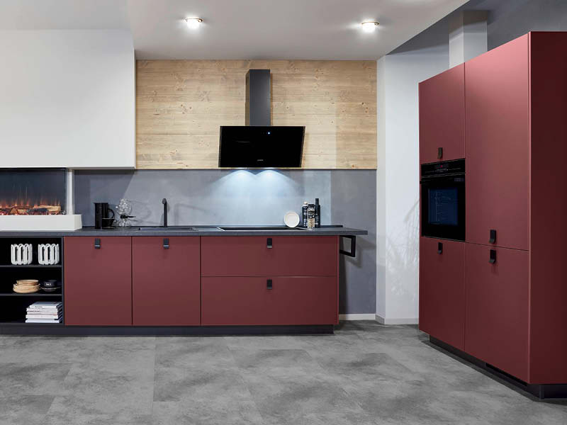 Rote, matte Küche in L-Form mit grauer Steinarbeitsplatte.
