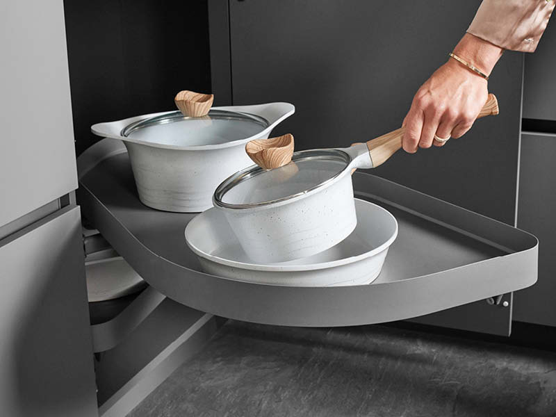 Frau nimmt Topf aus Küchenschrank mit Rondellauszug