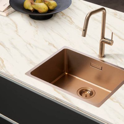 Bild einer bronzefarbenen Küchenspüle in Arbeitsplatte mit Marmoroptik in schwarzer Küche