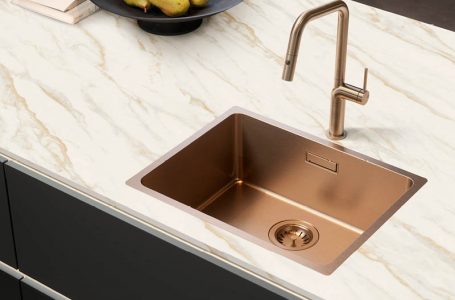 Bild einer bronzefarbenen Küchenspüle in Arbeitsplatte mit Marmoroptik in schwarzer Küche