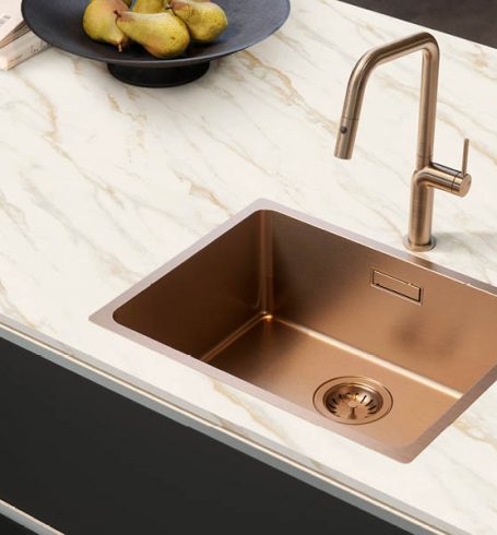 Bild einer bronzefarbenen Küchenspüle in Arbeitsplatte mit Marmoroptik in schwarzer Küche