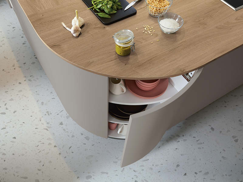 Runde Kücheninsel mit Holzarbeitsplatte, geöffnetem Eckschrank, Stauraum für Geschirr und kurzen Wegen beim Kochen.