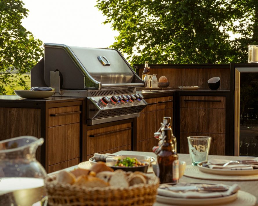 Outdoor-Küche von BURN mit gedecktem Tisch in Landschaft mit Bäumen