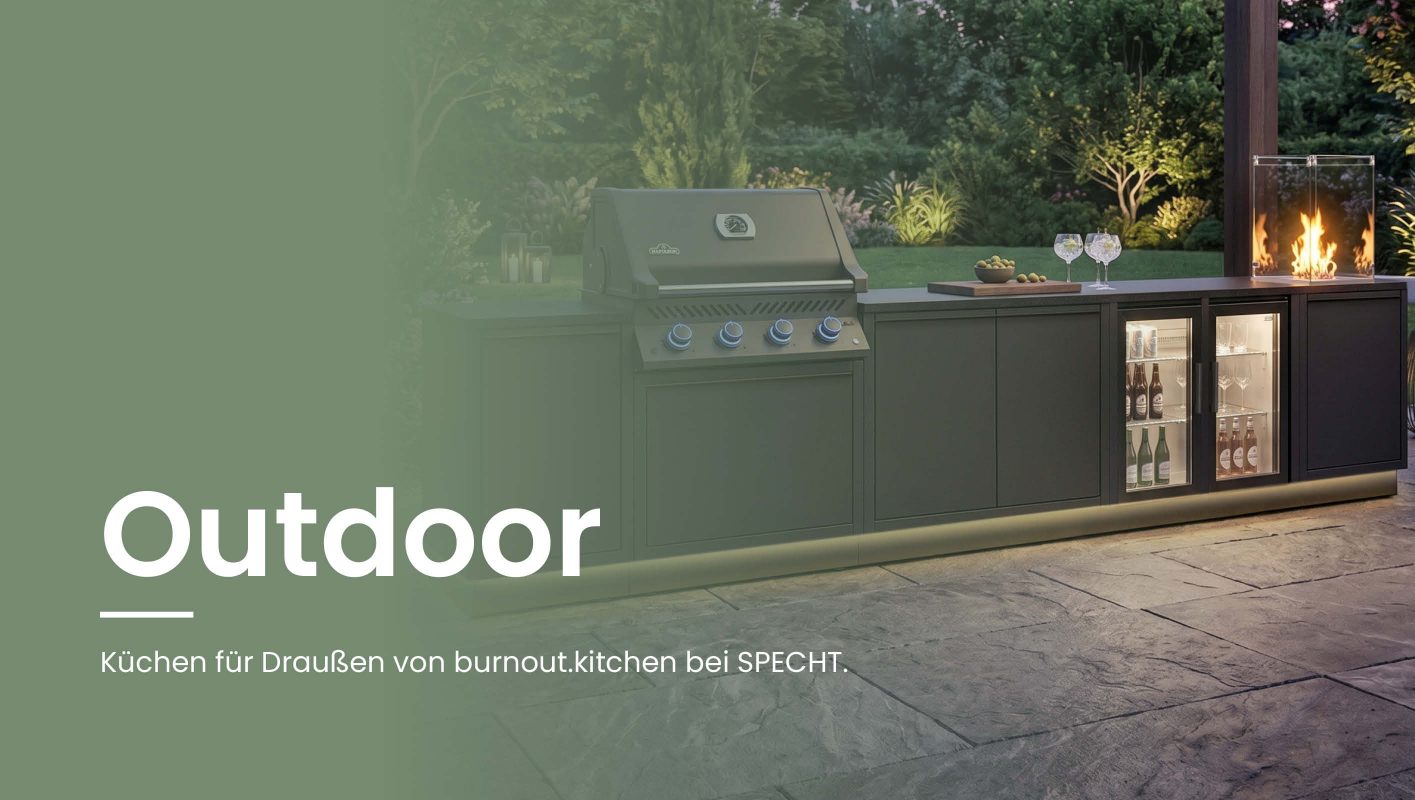 Breiter Website-Header mit moderner dunkler Outdoor-Küche von burnout.kitchen in einem Garten bei Abendstimmung. Zu sehen sind Grill, Getränkekühlschränke, Arbeitsfläche und Feuerstelle unter einer beleuchteten Pergola. Links steht der Text „Outdoor Küchen – Küchen für Draußen von burnout.kitchen bei SPECHT.“