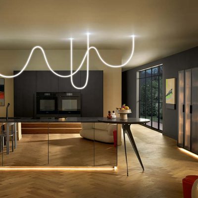 Moderne Küche mit dunkler Insel, warmen LED-Lichtleisten am Sockel und dekorativer Leuchte für stimmungsvolle Küchenbeleuchtung.