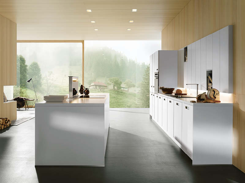 Helle weiße Designküche mit Kücheninsel, Holzverkleidung und großer Fensterfront; natürliches Licht ergänzt funktionale Einbauleuchten.