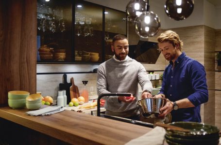 Zwei Männer stehen in gemütlicher Küche von Schüller und bereiten Essen an der Spüle zu