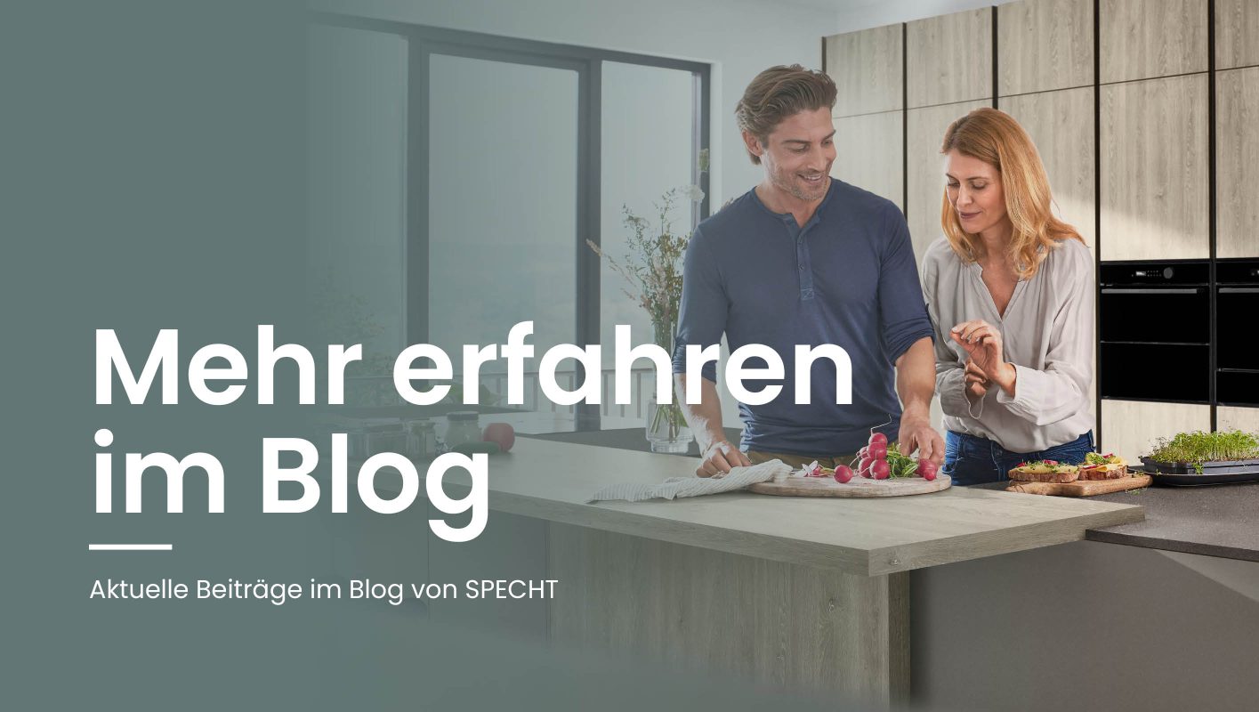 Paar beim gemeinsamen Zubereiten von Speisen in einer modernen Küche mit großzügiger Kücheninsel – Headerbild für den Blog von SPECHT Küchen.