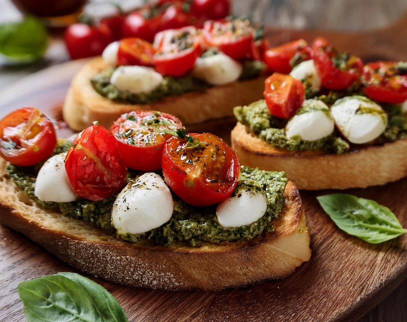 Geröstete Brotscheiben mit Pesto, Tomaten und Mozzarella als kulinarisches Highlight.