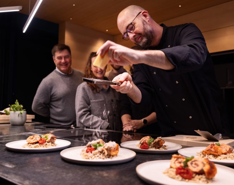 Koch richtet frisch zubereitete Gerichte beim Showkochen vor Gästen an.