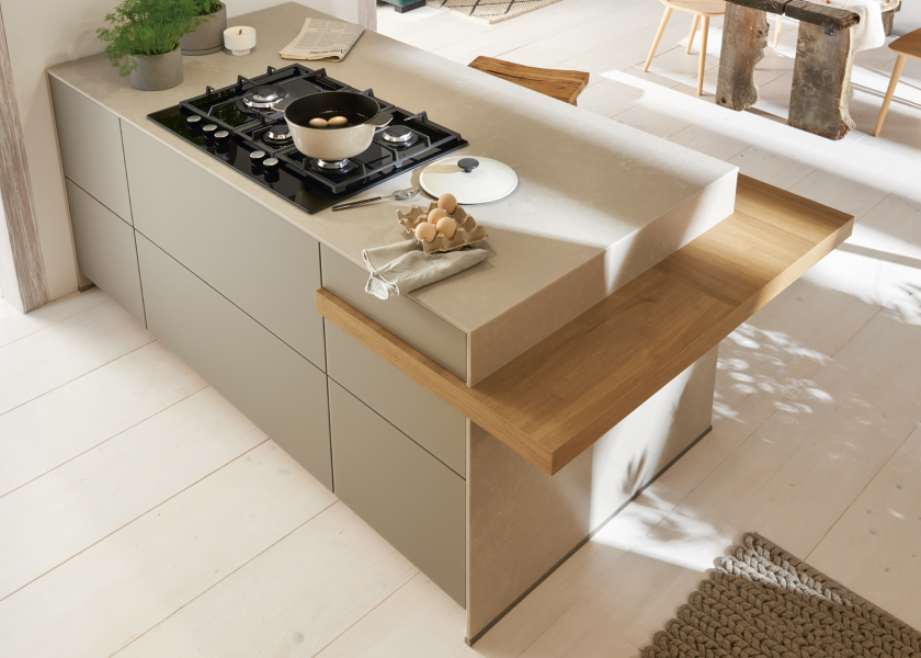 Detail einer modernen Kücheninsel mit Gaskochfeld, heller Arbeitsplatte und integrierter Holztheke – funktionale Küchenplanung von SPECHT Küchen.