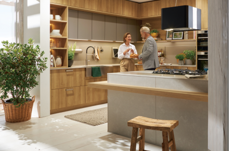 Paar in einer modernen Küche mit Holzfronten und Kücheninsel – gemeinsames Kochen und wohnliche Küchenatmosphäre bei SPECHT Küchen.